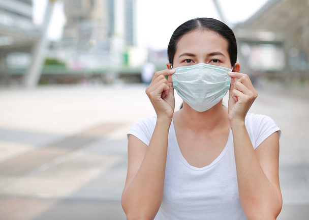 Person wearing protective mask against transmissible infectious diseases and as protection against pollution and the flu. Asian woman commuter in public area. - Fotografie, Obrázek