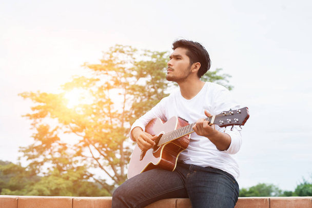 Joven hipster hombre tocando la guitarra para relajarse en sus vacaciones, enj
 - Foto, imagen