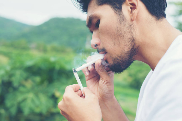 Young hipster man taking rest, smoking cigarette with nature and - Foto, imagen