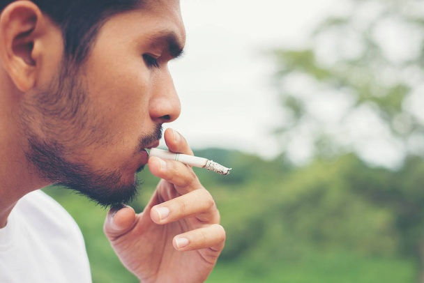 junger Hipster-Mann beim Ausruhen, Zigarette rauchen mit der Natur und - Foto, Bild