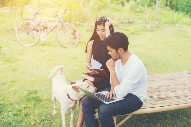 joven educación pareja sentado en el banco jugar con perro en el
 - Foto, Imagen