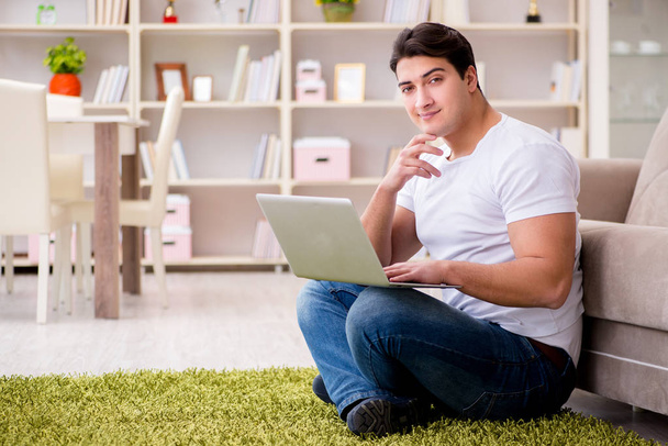 Man working on laptop at home on carpet floor - Photo, Image