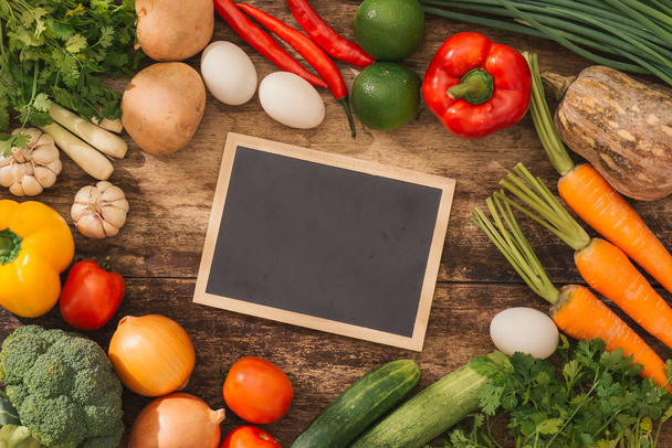 Cooking classes concept. Fresh vegetables around chalkboard on table. - Photo, Image