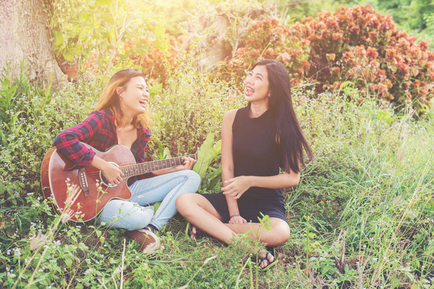 Junge Teenagerin schaut ihre Freundin beim Gitarrespielen an, - Foto, Bild