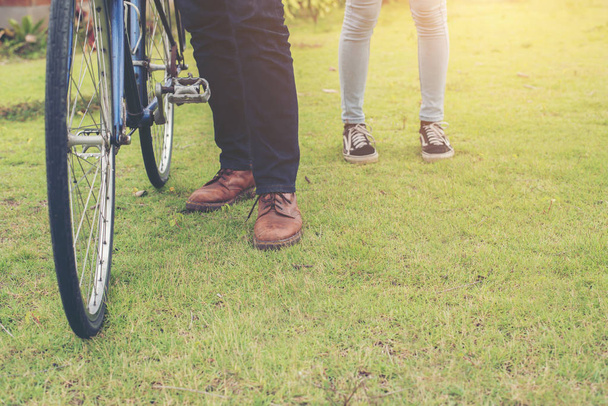The legs of young couple standing near bicycles in the nature pa - Photo, Image