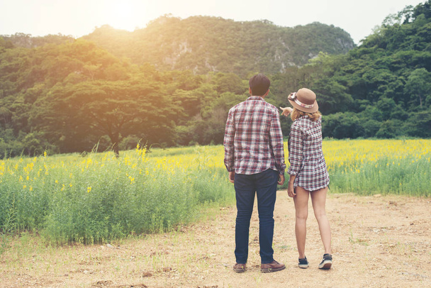 Jeune couple hipster faisant une promenade sur un beau champ de fleurs
. - Photo, image