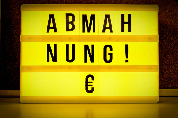 Panel iluminado con la palabra alemana "Abmahnung" en inglés "written warning" para simbolizar una advertencia con Upload file-sharing files yellow
 - Foto, Imagen