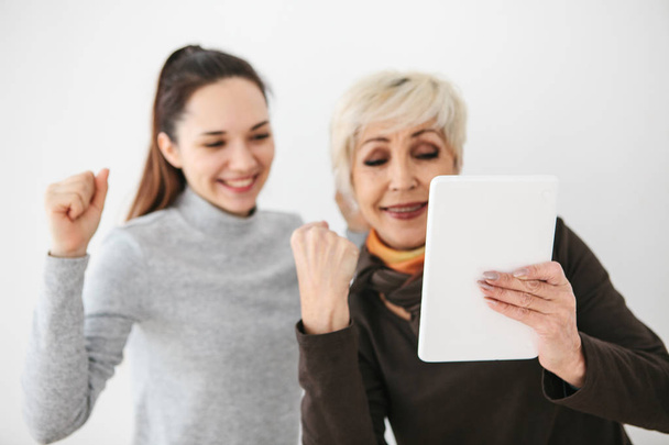 Une jeune fille et une femme âgée regardent quelque chose d'intéressant sur la tablette et sont heureux. Communication, passe-temps commun, émotions positives entre les gens
. - Photo, image