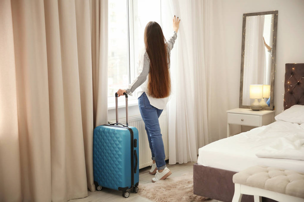 Young woman with luggage in hotel room - Фото, зображення