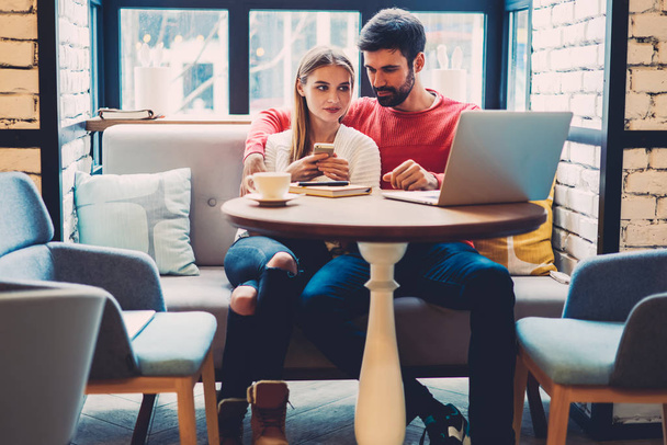 Romantic couple in love viewing photos of friends from social networks via modern laptop resting in cafe, lovers spending time together enjoying watching movie online in comfortable coffee shop - Foto, Imagem