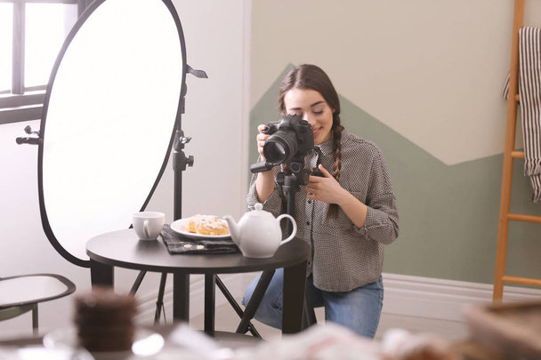 Young woman with professional camera taking food photo in studio - Fotó, kép
