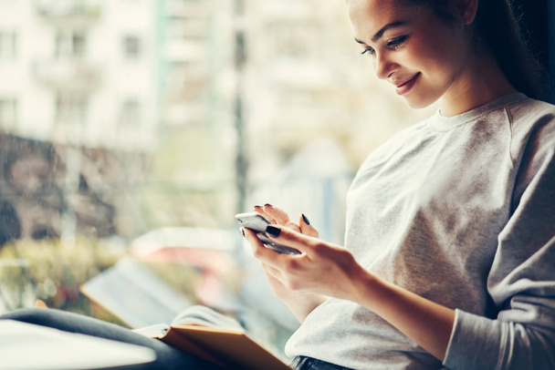 Cropped image of happy hipster girl having funny online chatting with friends in social networks on smartphone connected to wifi.Positive young woman enjoying leisure time in coffee shop with gadget - Photo, Image