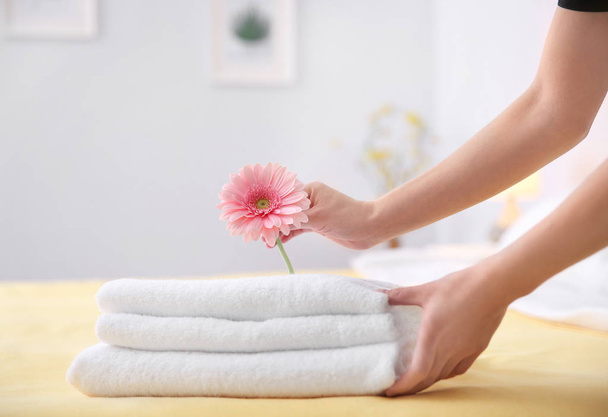 Mladá služka uvedení květin na zásobník ručníků v hotelovém pokoji - Fotografie, Obrázek