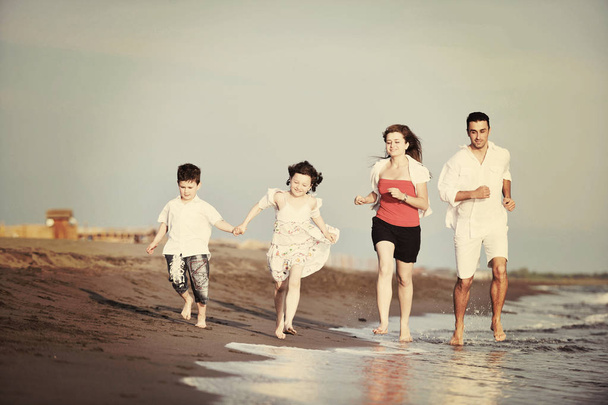 幸せな若い家族はビーチで楽しんでいます - 写真・画像