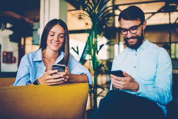 Male and female friends ignoring real communication sending messages via mobiles during meeting,smiling colleagues resting during break in cafe using phones for reading online news addicted to gadgets - Fotó, kép