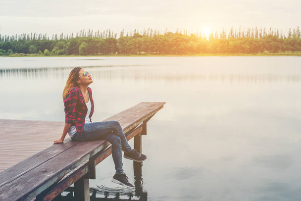 Молодая красивая хипстерша, сидящая на пирсе озера, расслабленная
  - Фото, изображение