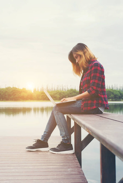 Young happy hipster woman working with her laptop sitting on pie - Photo, image