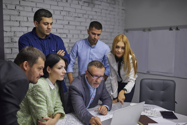 Crew of pensive creative designers dressed in formal wear browsing useful information while collaborating indoors.Group of skilled colleagues using modern technology during working process in office - Фото, зображення