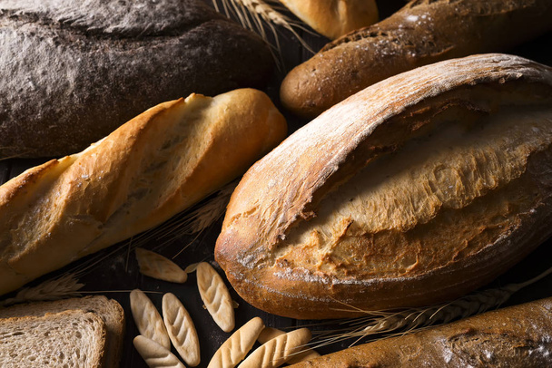 Bakery - gold rustic crusty loaves of bread and buns on black chalkboard background. - Fotografie, Obrázek