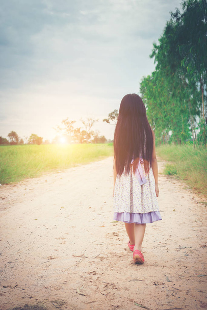 Little girl with long hair wearing dress is walking away from yo - Fotó, kép