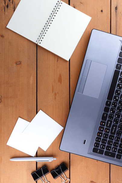 Laptop op een houten achtergrond, een baan op een oude tafel, een smartphone en een laptop, een pen en glazen op de werkplek, kopiëren ruimte, kantoorruimte in een minimalistische stijl, de plek voor de ontwerper - Foto, afbeelding