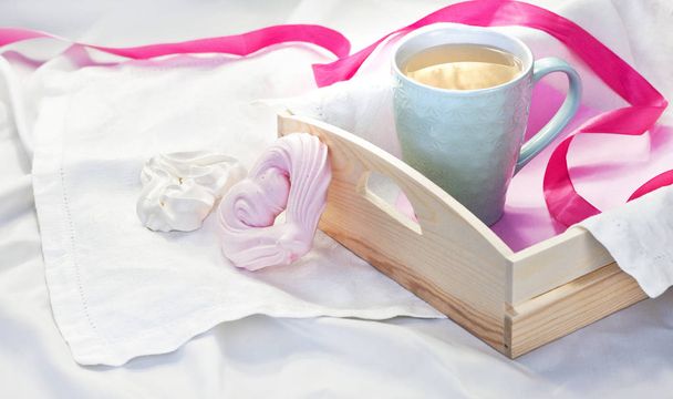 Поднос с чашкой горячего чая и домашней безе в виде сердца в постели на белом текстиле. Горячий напиток Love Breakfast in bed Утро
 - Фото, изображение