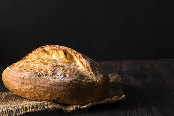 Fırın ekmek üreticileri - altın rustik huysuz somun ekmek ve siyah arka plan üzerine buns. - Fotoğraf, Görsel