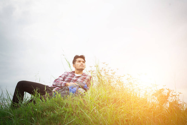 Hipster młody człowiek odpocząć na łąkach wędrówkach, poszukaj  - Zdjęcie, obraz