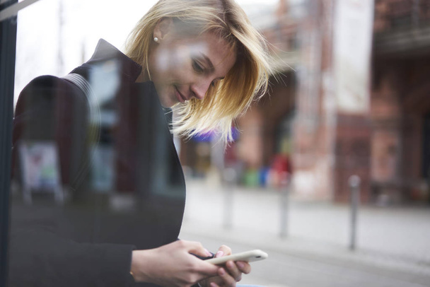 Attractive blonde female traveler dialing number of taxi standing on blurred urban setting copy space area for advertising, charming hipster girl using 4g connection for blogging in social networks - Foto, immagini