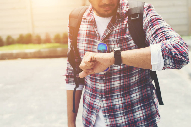 Jeune homme regardant sa montre à main avant d'aller voyager avec bac
 - Photo, image