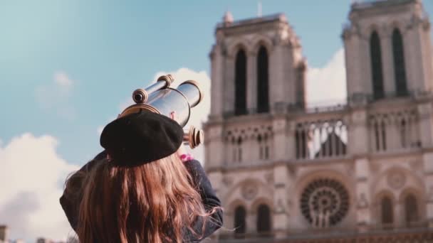 Girl child in beret looks through coin binocular. Slow motion. Notre-Dame de Paris. Female kid using view telescope. - Filmati, video