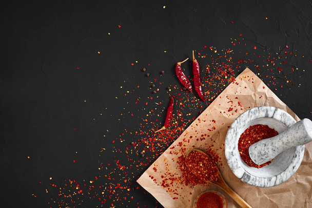 Αποξηραμένο και θρυμματισμένο κόκκινο πιπέρι τσίλι σε πέτρινο Γουδί. Χώρο αντίγραφο - Φωτογραφία, εικόνα