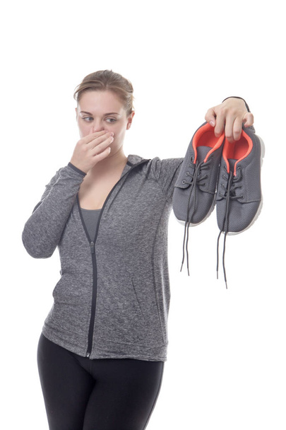 modelo de fitness femenino sosteniendo sus zapatillas apestosas
 - Foto, Imagen