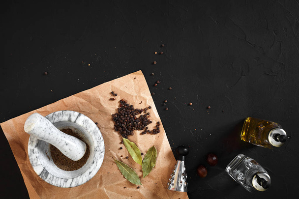 White mortar and pestle with dried peppers in flat lay on black background - 写真・画像