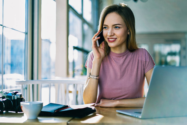 Charming blonde female administrative manager having phone conversation talking about business planning, professional attractive editor making booking calling to service satisfied with good offer - 写真・画像