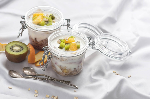 Здоровый завтрак из йогурта с мюсли и фруктами в стеклянной банке в лоток в постели. Здоровый завтрак
 - Фото, изображение