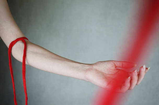primo piano della mano della donna con la corda rossa su sfondo grigio - Foto, immagini