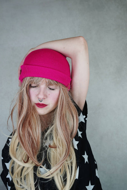 Portrait of young blonde woman in pink hat on background - Foto, imagen