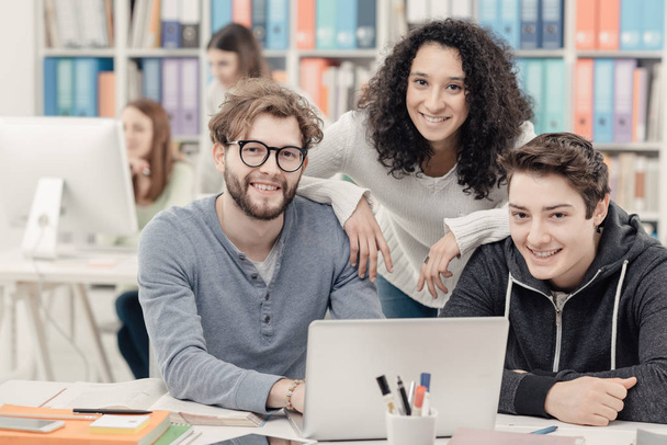 Group of happy students connecting together with a laptop and smiling, teamwork and education concept - Фото, зображення
