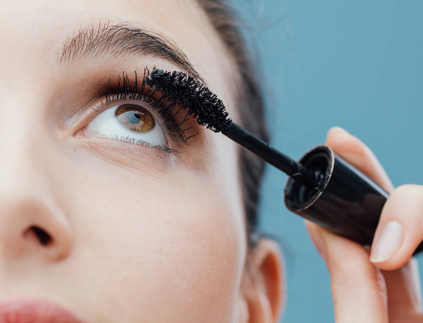 Woman applying mascara on her lashes, make up and cosmetics concept - Foto, Bild