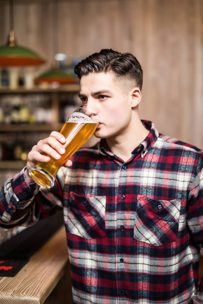 Az ember iszik sört. Jóképű fiatalember sört ülve a bárban számláló - Fotó, kép