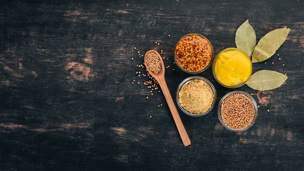 Assortment of mustard in sauces. Spices On a black wooden background. Top view. Copy space for your text. - Foto, Imagen