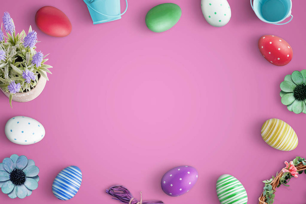 Top view of Happy Easter composition with flat lay colorful eggs and decorations. Pink background. - Фото, зображення