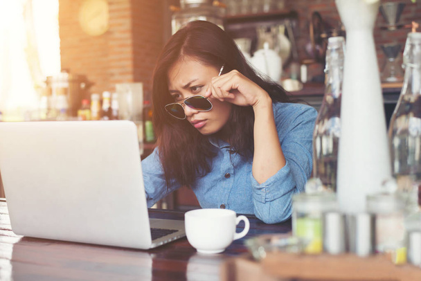 Mujer hipster bastante joven sentado en un café con su computadora portátil, lo
 - Foto, imagen