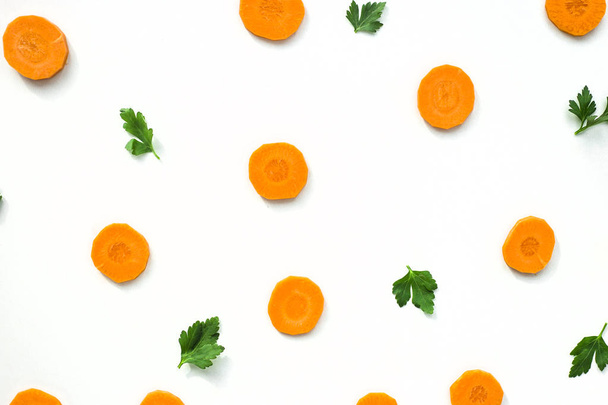 Brillantes bucles redondos de zanahorias y ramitas verdes de perejil sobre un fondo blanco. Concepto de comida saludable. Vista superior, plano
 - Foto, imagen