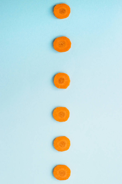 Brillantes bucles redondos de zanahorias sobre un fondo azul. Concepto de comida saludable. Vista superior, plano
 - Foto, imagen