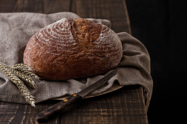 Freshly baked  bread with  kitchen towel and wheat - Valokuva, kuva