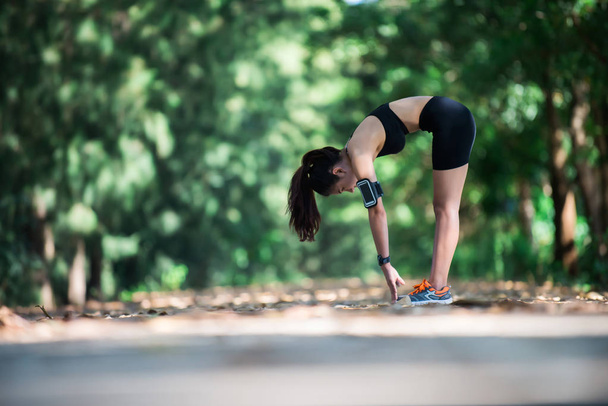 Joven mujer fitness estirando las piernas antes de correr
. - Foto, imagen