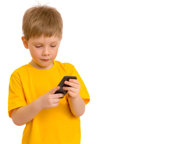 Een kleine jongen communiceert op een mobiele telefoon. - Foto, afbeelding