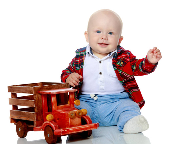 A little boy is playing with a toy car. - Zdjęcie, obraz